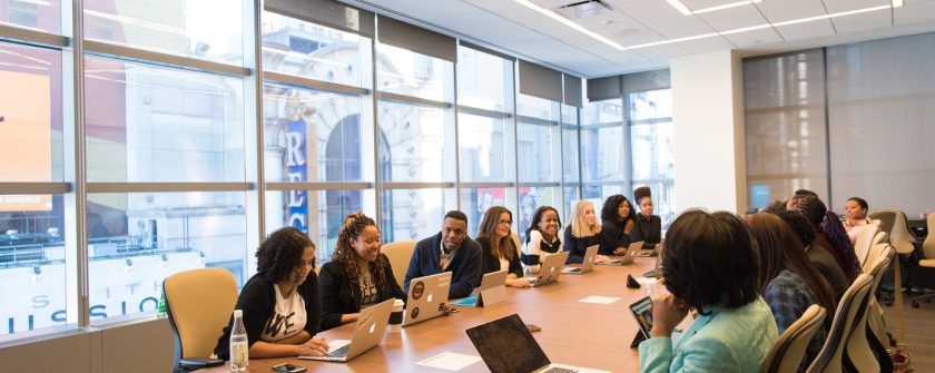 group of people sitting beside rectangular wooden table with laptops
